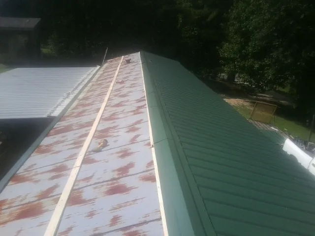 Old rusted panels beside newly installed green metal roofing — Wind Damage Roof Repair by Roofing Brothers in Lovelock