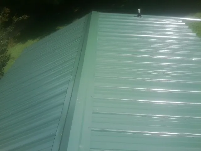 New green metal panels meeting at the ridge of a roof — Flat Roof Repair work by our crew in Lovelock