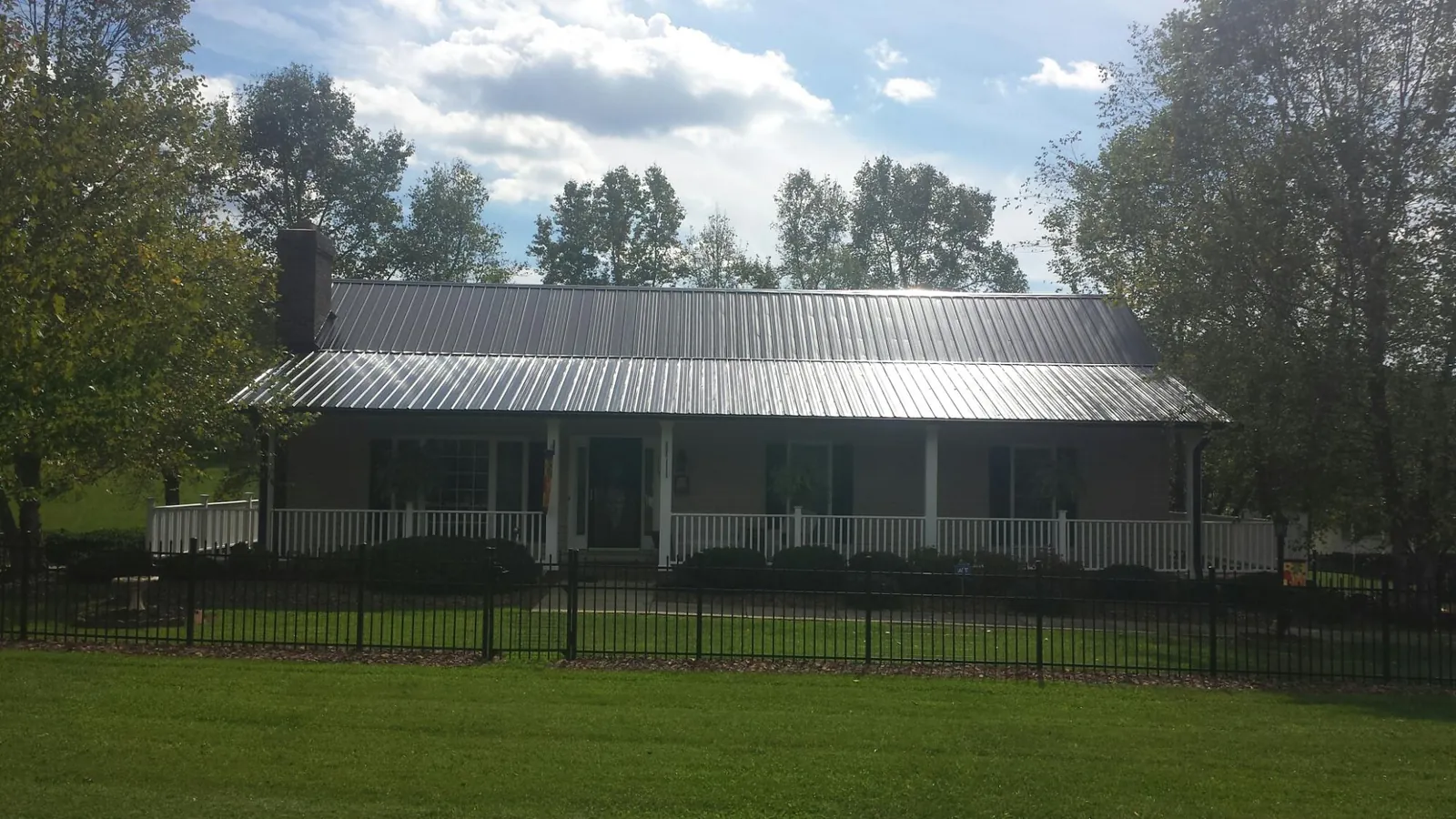 Gray metal roof on a brick ranch with a full width front porch — Gutter Guard Installation work by our crew in Lovelock