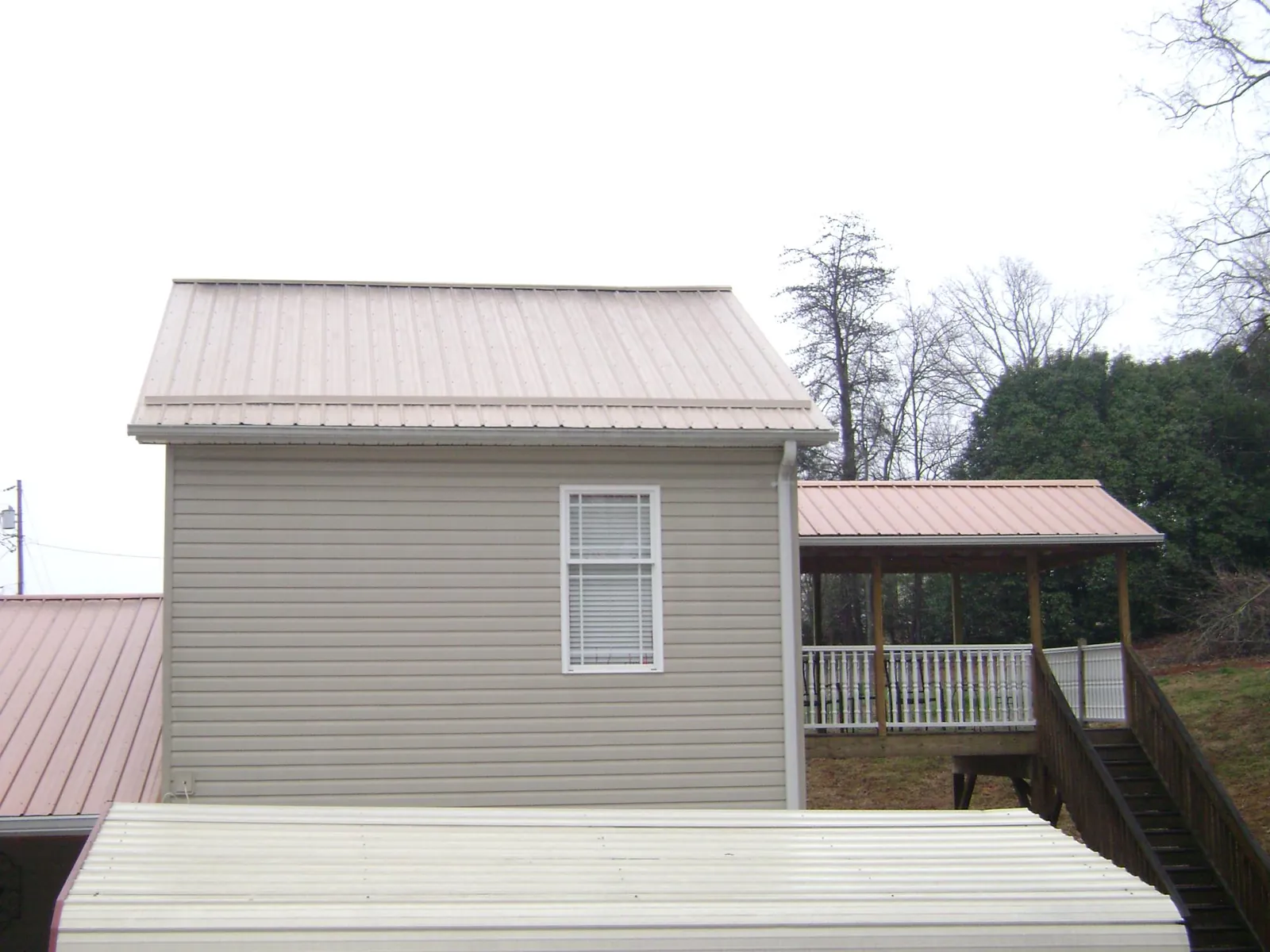 Tan metal roofs on a two story addition and attached porch, from a Roof Replacement job in Lovelock