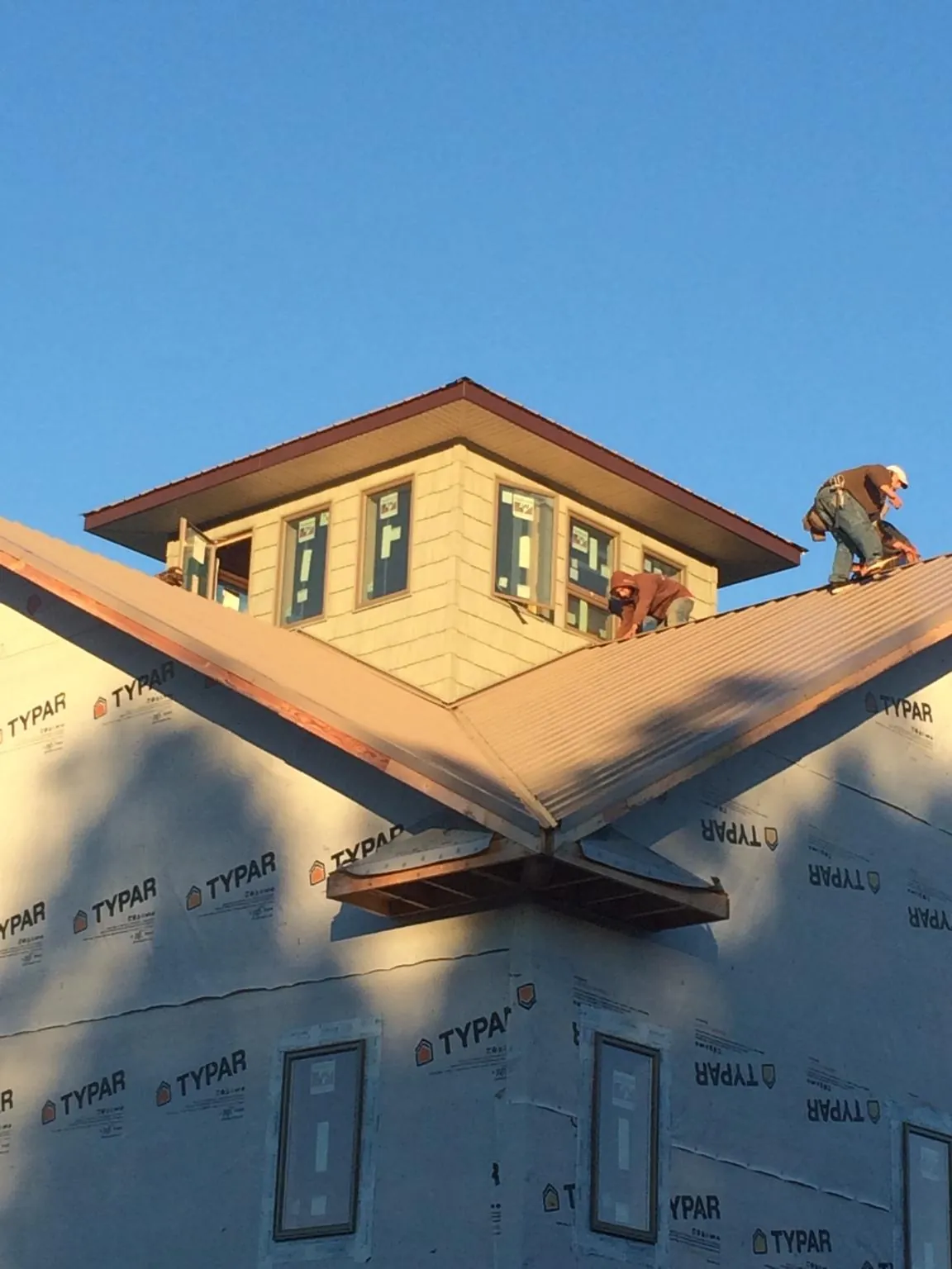 Roofers working around a rooftop cupola on a new metal roof at sunset — Roof Waterproofing in Lovelock by Roofing Brothers